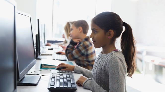 a line of seated children working at a computer